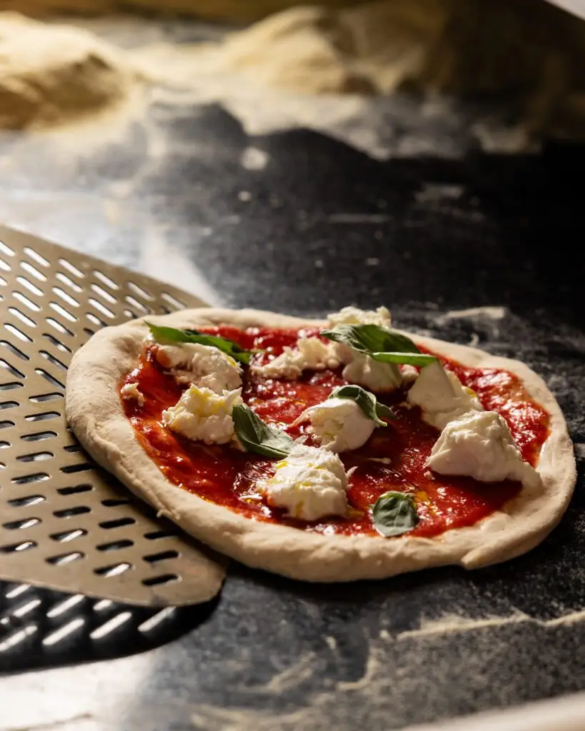 Eine ungebackene Pizza mit Mozarella und Basilikum, die gleich in den Ofen geschoben wire