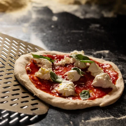 Eine ungebackene Pizza mit Mozarella und Basilikum, die gleich in den Ofen geschoben wire