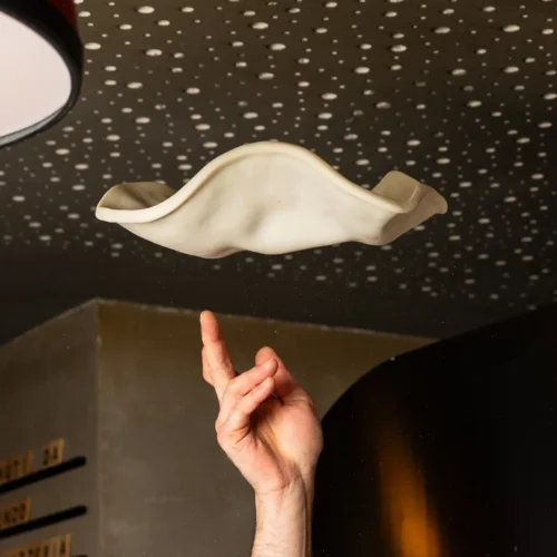 Pizzabäcker wirft gerade den frischen Pizzateig in die Luft