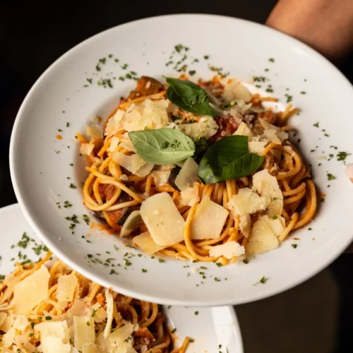 zwei Teller mit leckerer Pasta, garniert mit frischem Basilikum und Parmesan