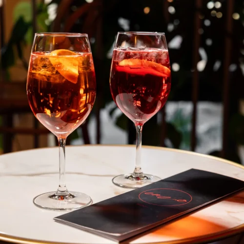 Bunte Drinks bei Enzo mit Eiswürfeln, frischen Orangenscheiben in Weingläsern